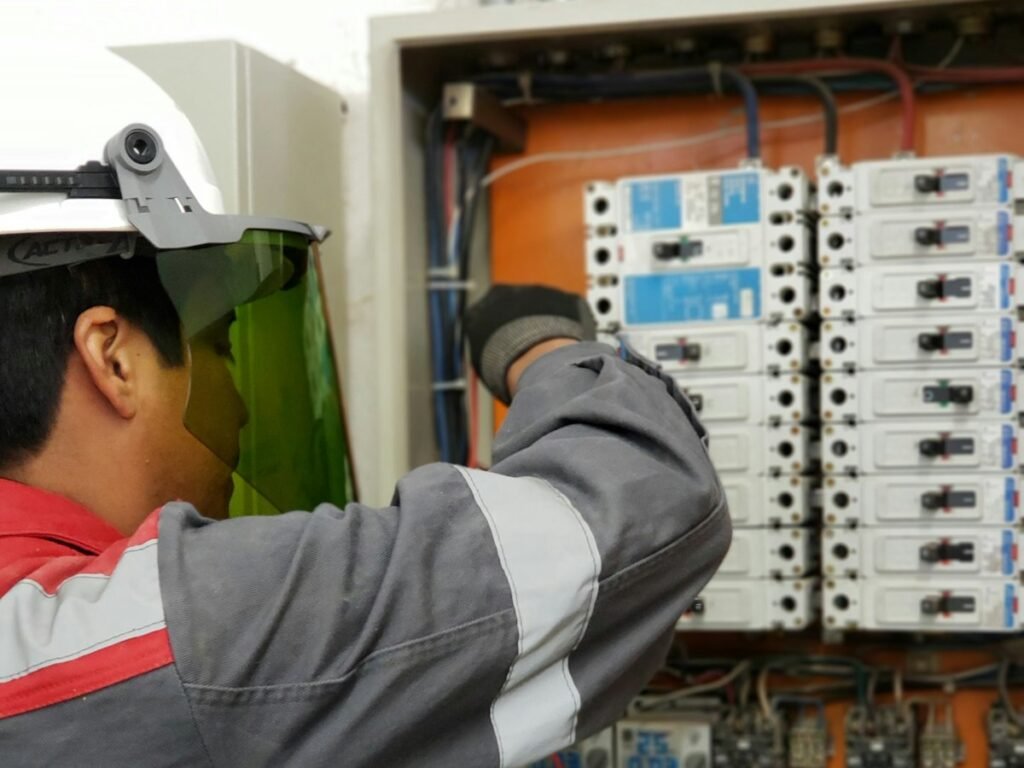 Electricista con casco y proteccion facial probando un tablero electrico